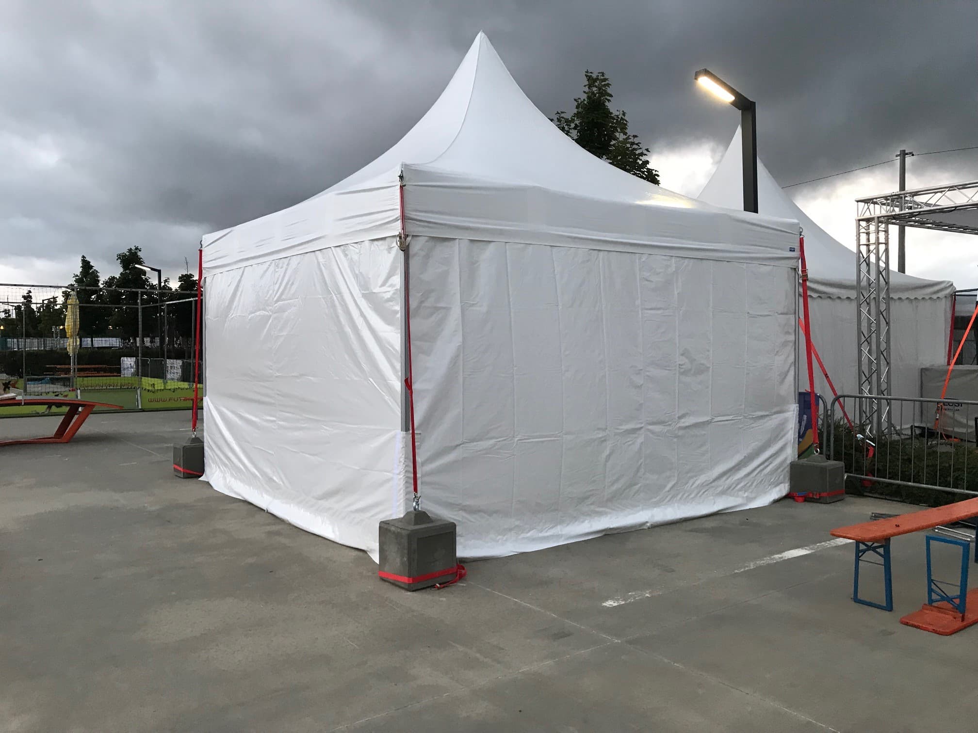 White LP Tent pagoda with concrete ballast weights at an outdoor venue