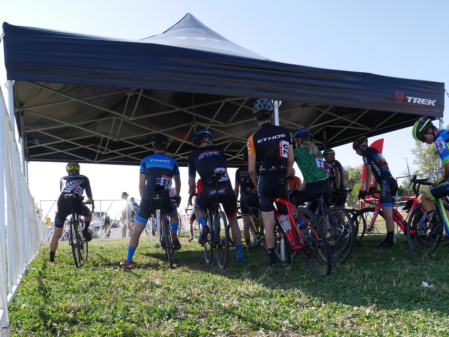 Professional cyclists sheltering beneath an LP Tent at a race event